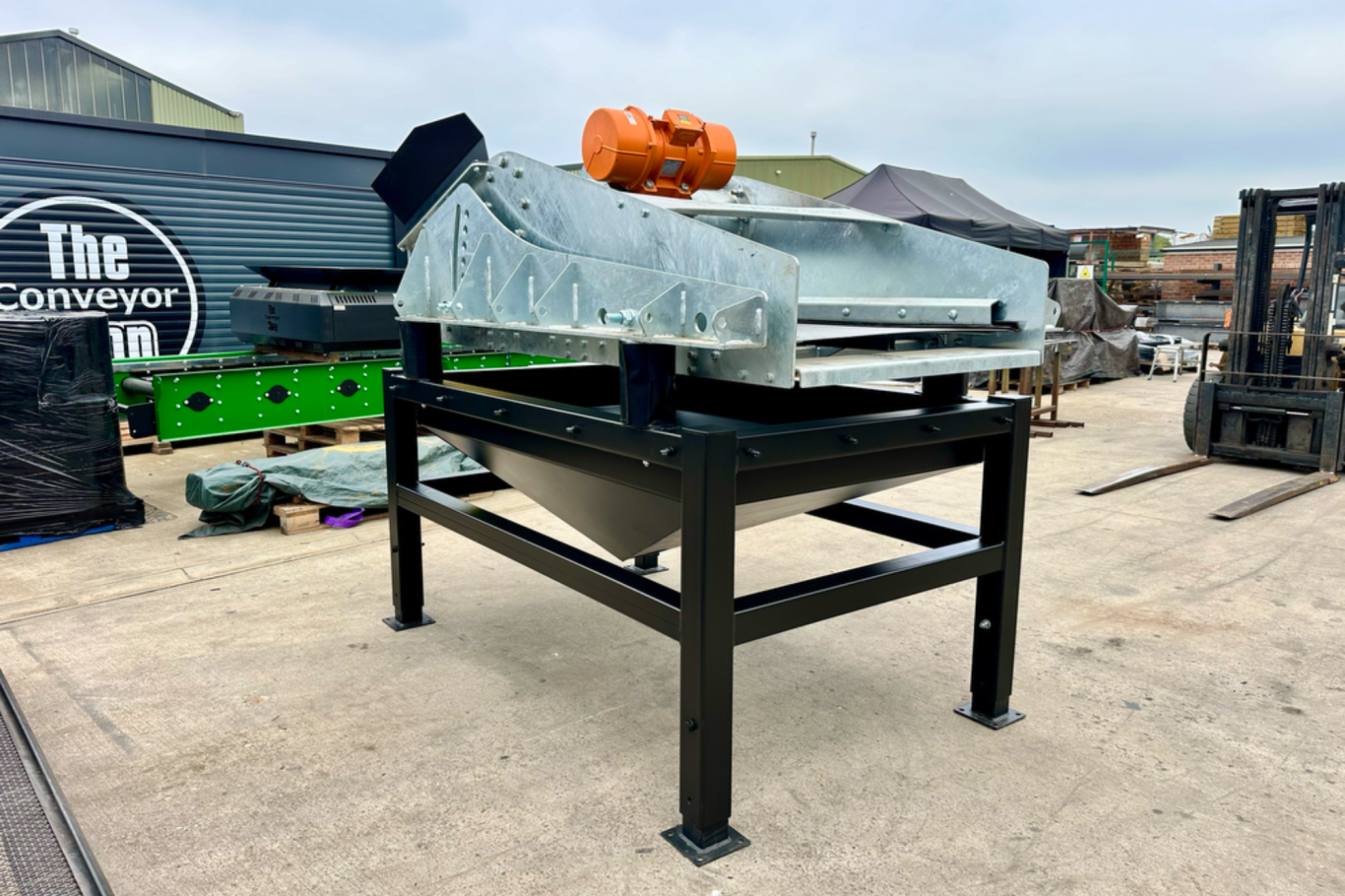 Metal processing equipment on a sturdy black frame in an outdoor setting.